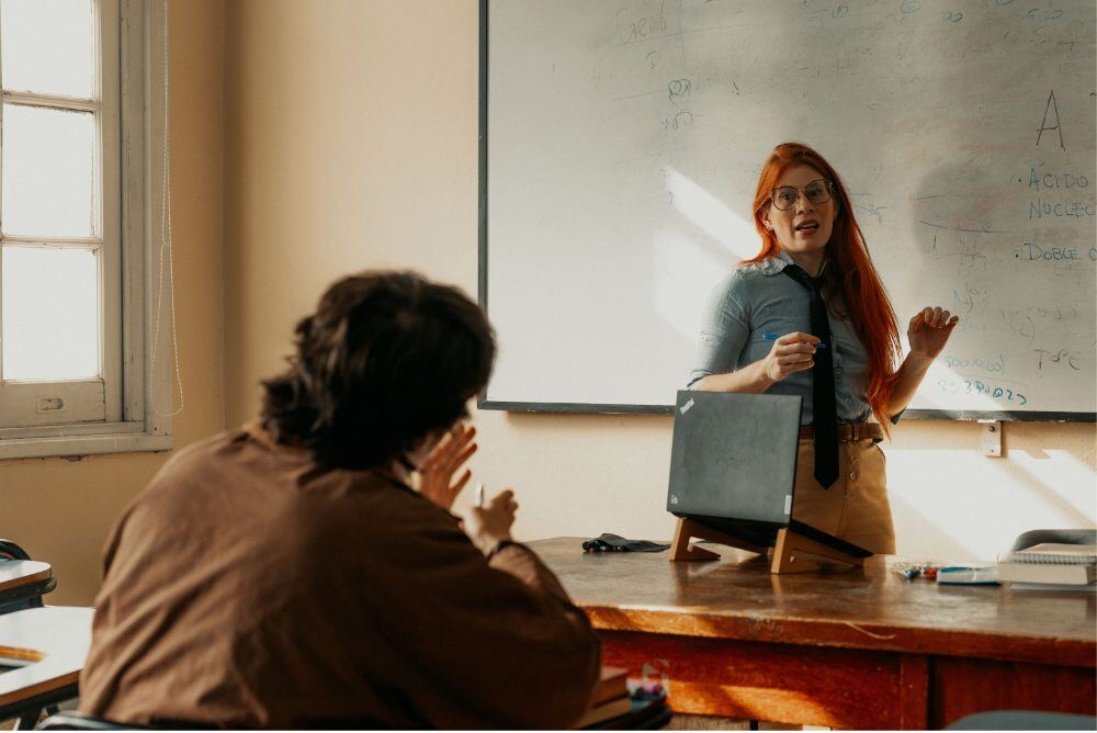 A teacher talking with a student in a sunlit classroom